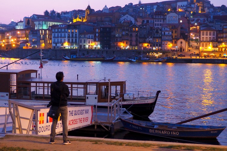 Man standing on the riverbank at night in Porto, Portugal. 