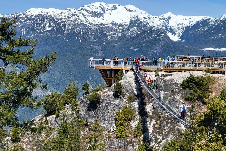 summit viewing platform at Sea to Sky Gondola in Squamish with view of snow-capped mountain in the distance and suspension bridge 