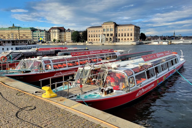 sightseeing boat tour in Stockholm Sweden, docked on the river in front of the Stockholm Royal Palace in Gamla Stan old town