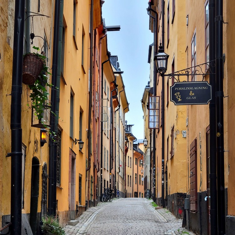An uneven cobblestone road splits through tall and thin buildings in Gamla Stan, things to do in Stockholm Sweden