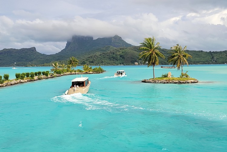 Bora Bora airport boat transfers to hotels. First view of the deep blue water of Bora Bora with lush green volcano in the backdrop