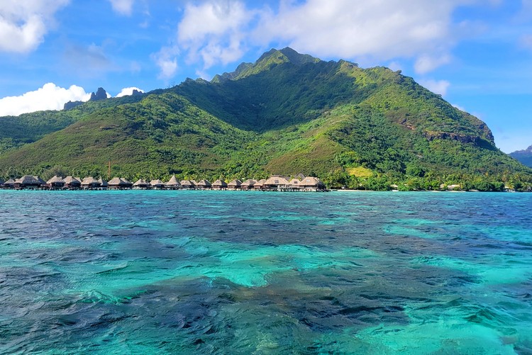 overwater bungalows on Moorea island, view of the clear blue water and green mountain from the ocean