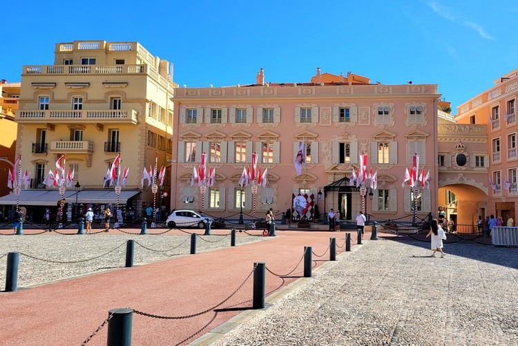 Palace Square in Monaco, pink building with unique architecture, flags celebrating Prince Rainier III anniversary