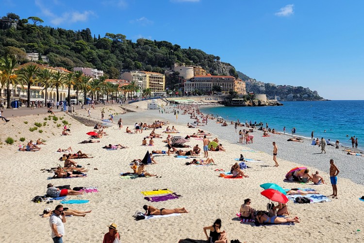 View of People on the beach at Plage des Ponchettes facing east towards Castle of Nice, France, tips for travel to Nice
