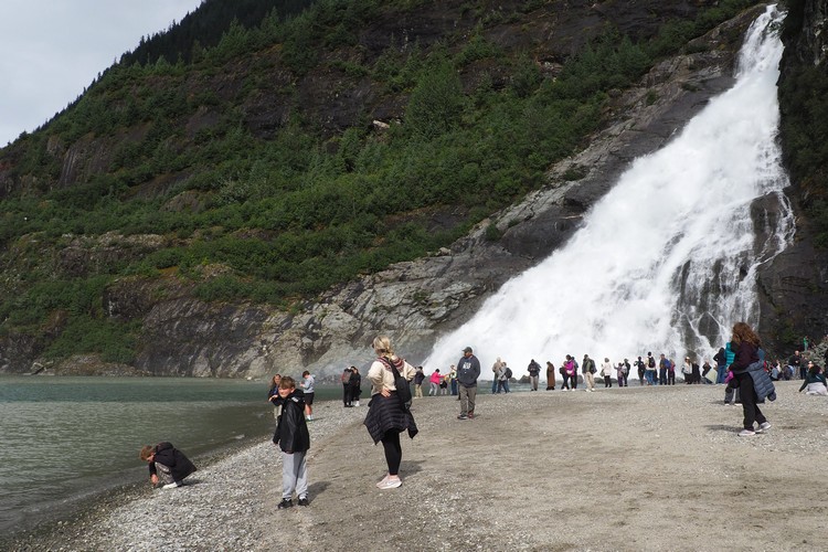 Tourists admire the views at the base of Nugget Falls near Mendenhall Glacier in Juneau Alaska, popular cruise ship excursion